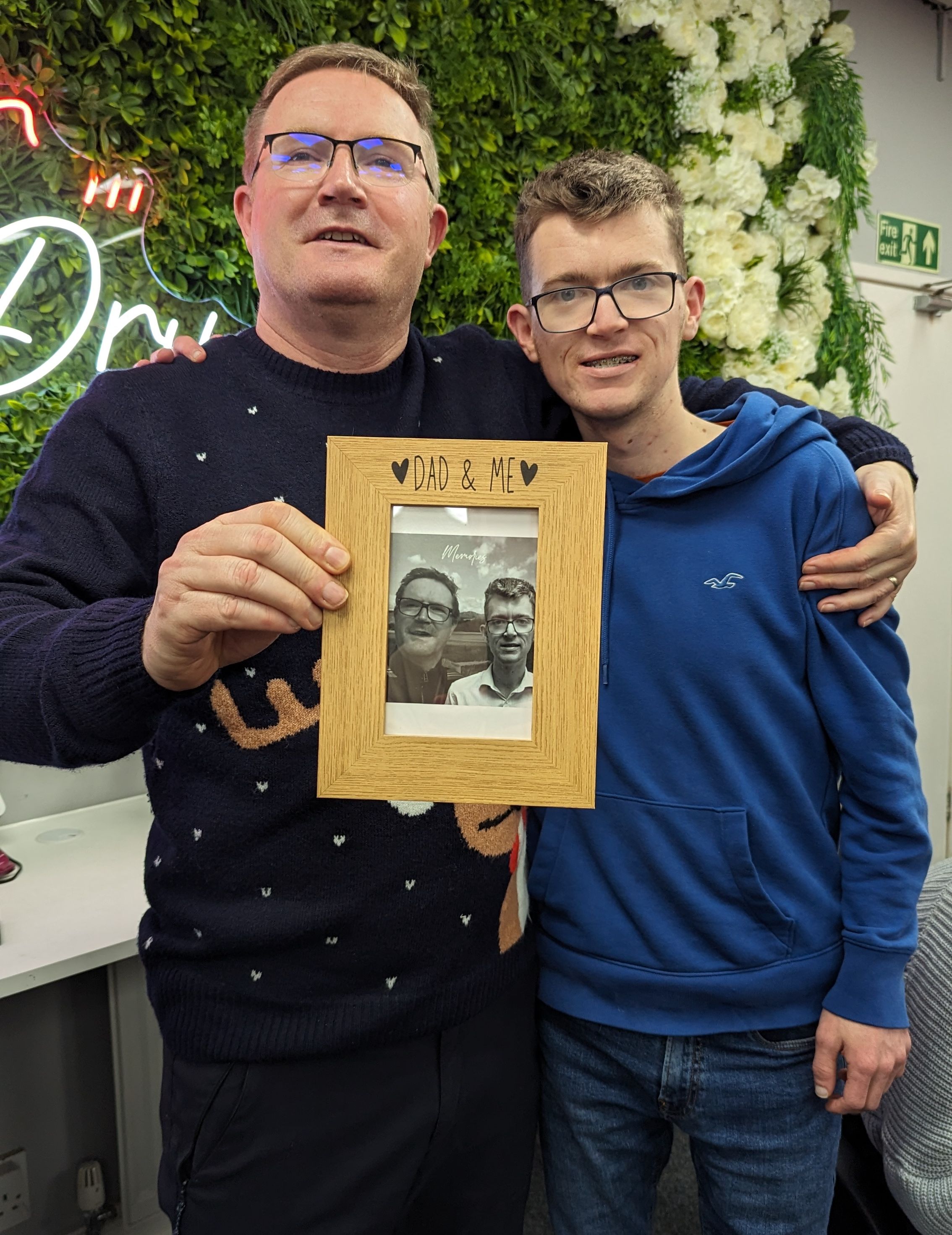 2 men smiling holding a photo frame