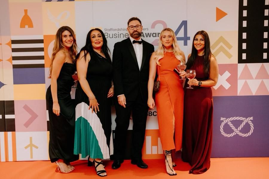 5 people in a line dressed smart for an awards ceremony.