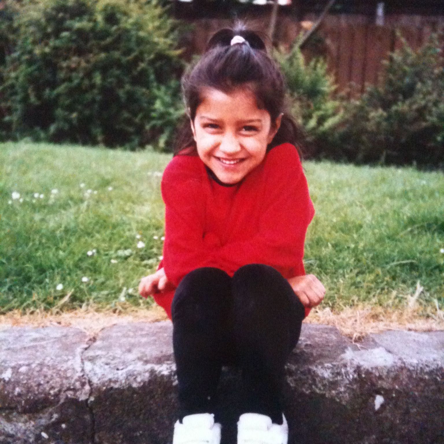 Smiling young girl sitting on a wall.