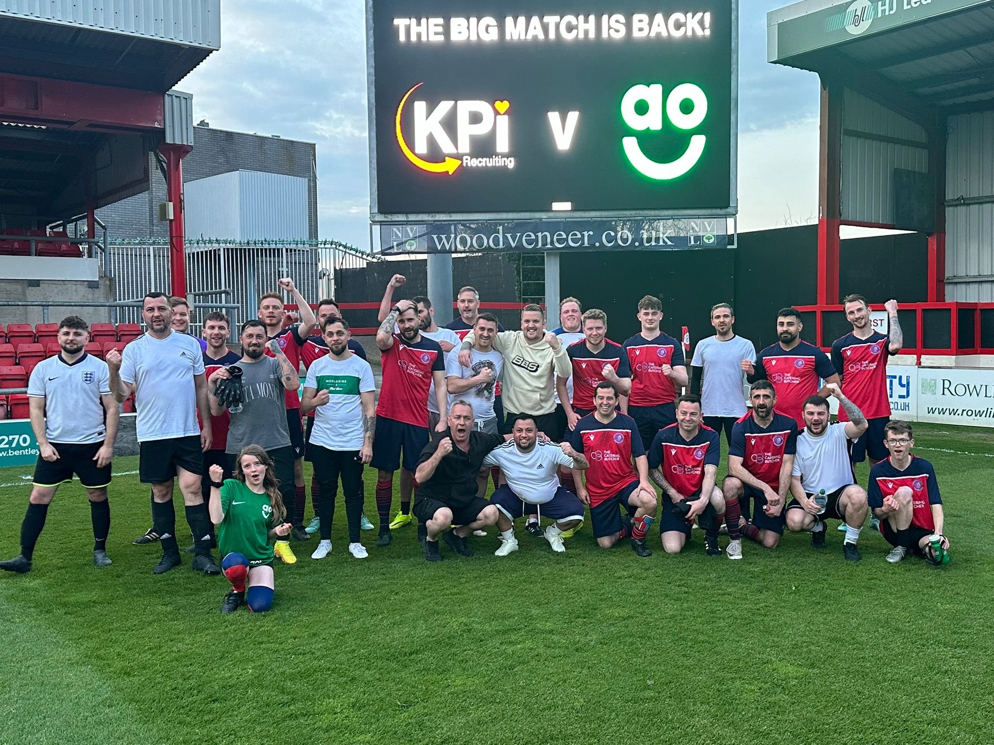 Two football teams posing for a photo on the pitch.