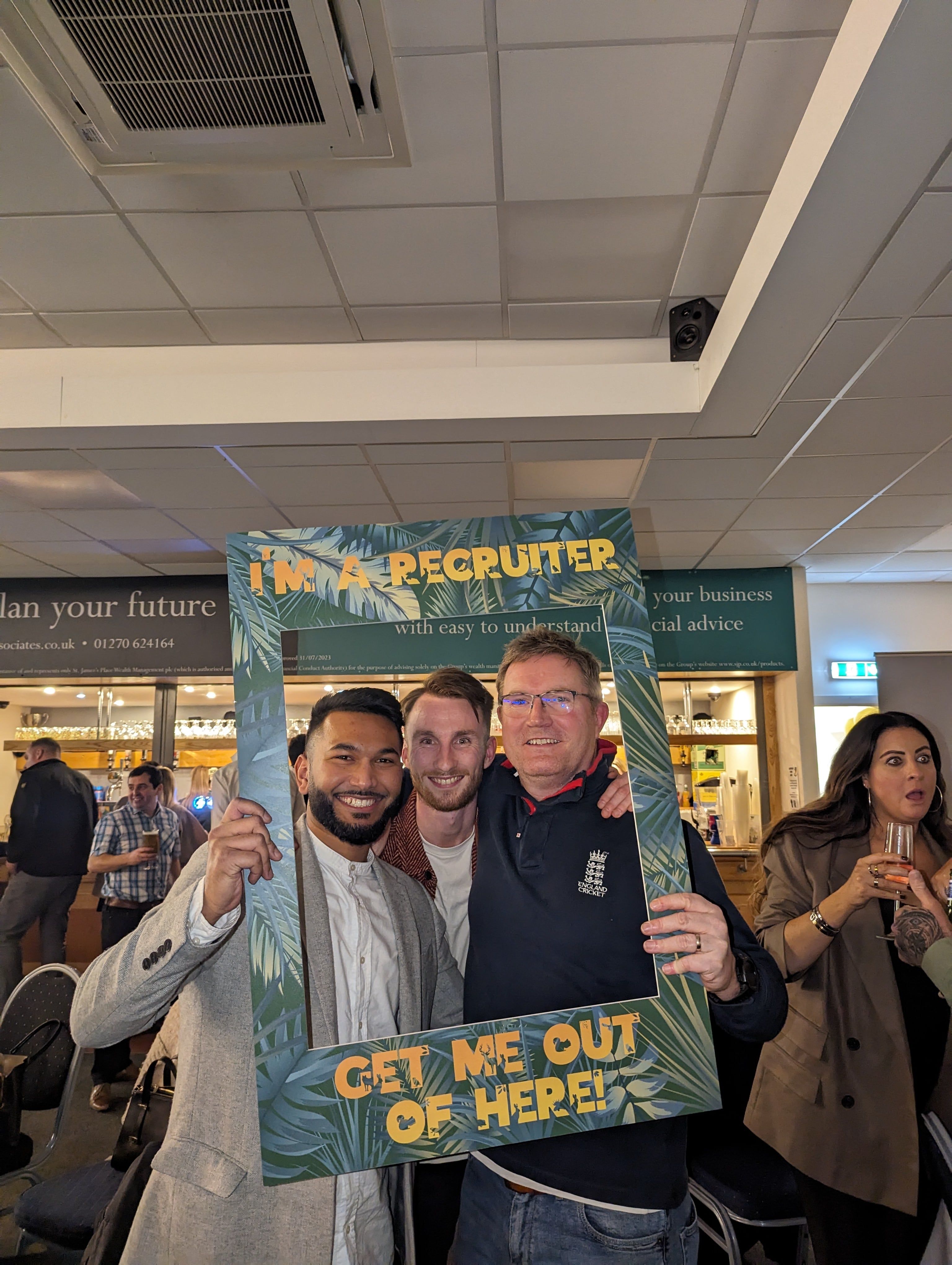 3 male colleagues posing in a selfie frame at a party.