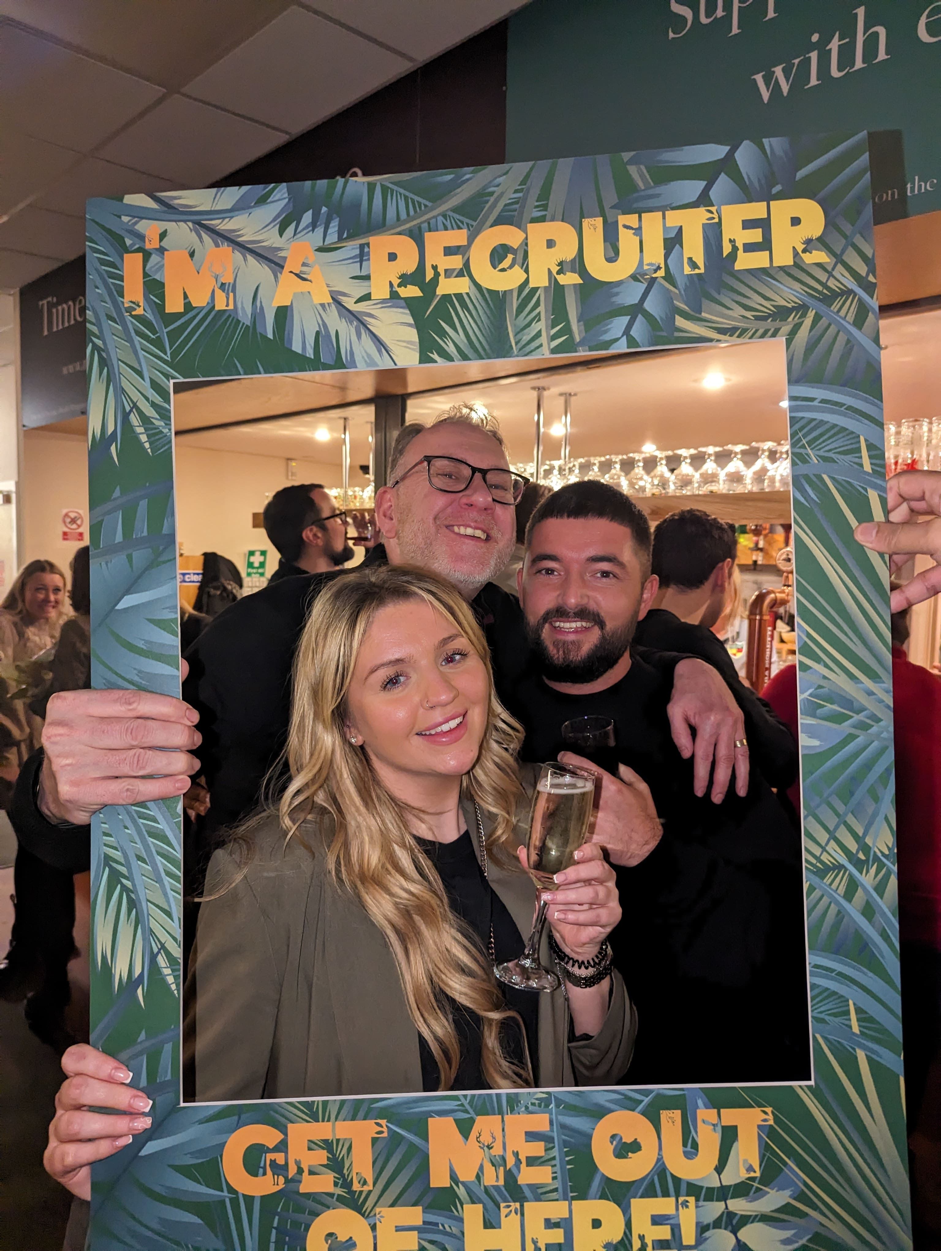 two males and a female posing in a selfie frame at a bar.