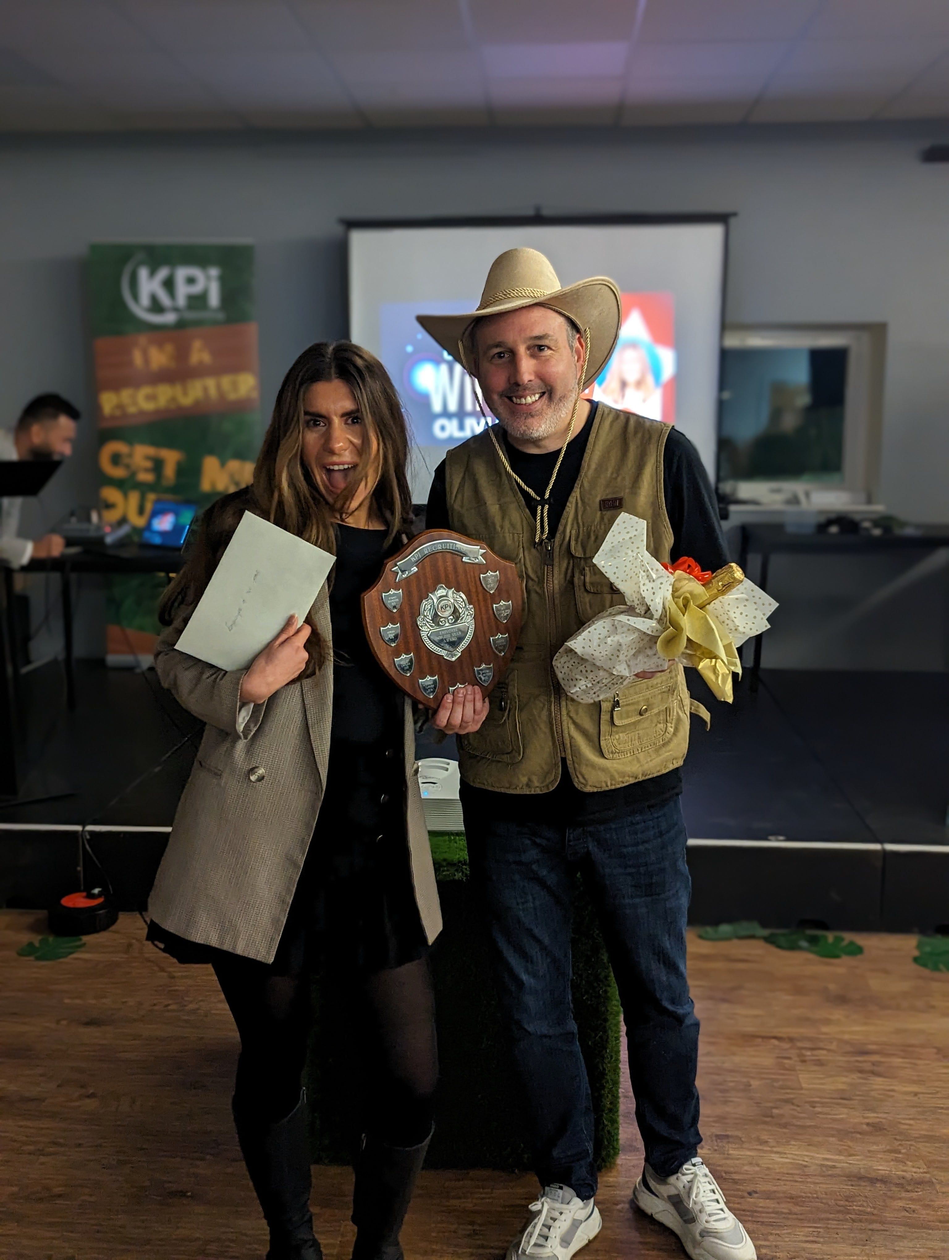 2 colleagues posing holding awards.