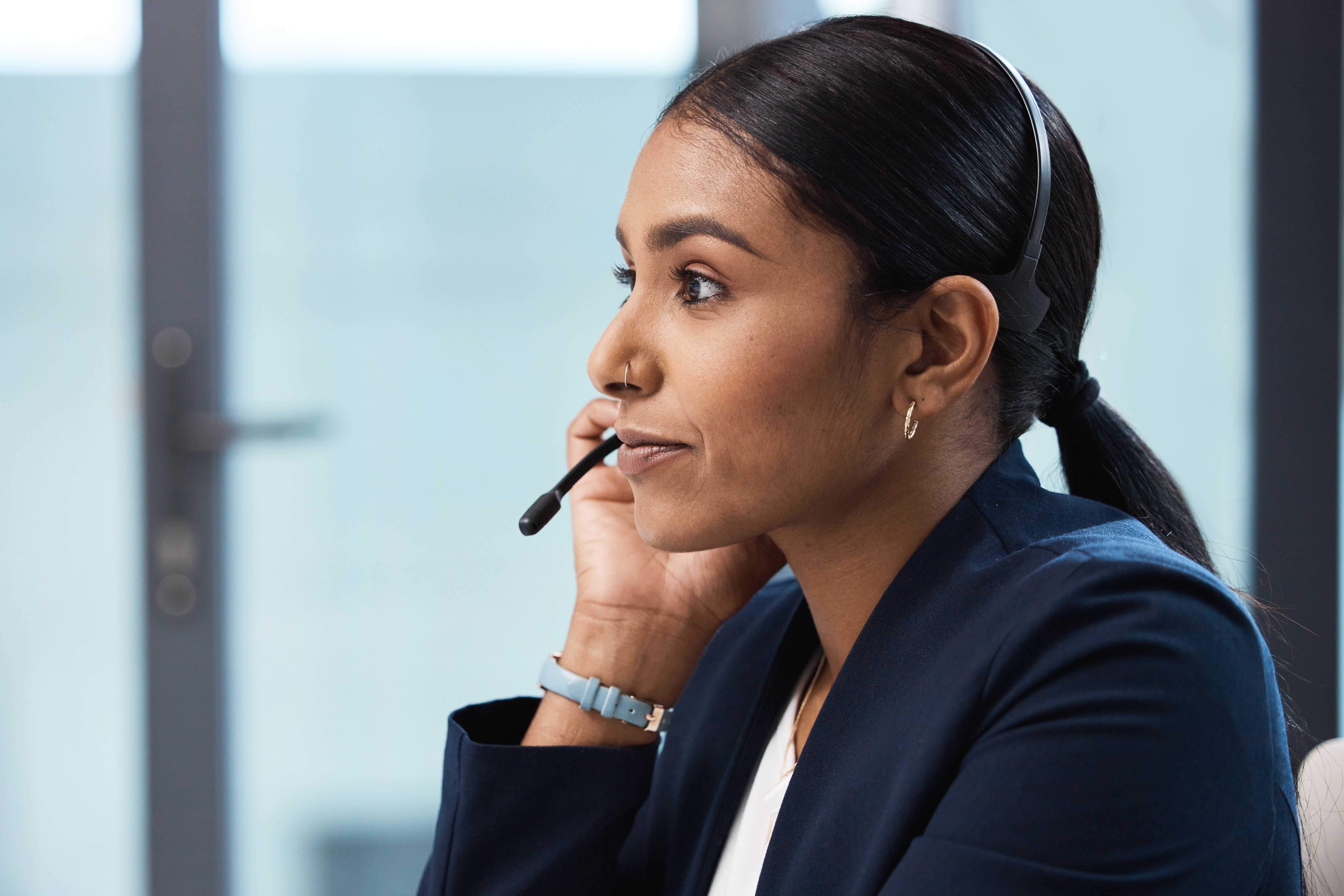 A woman with a headset in business attire in an office.