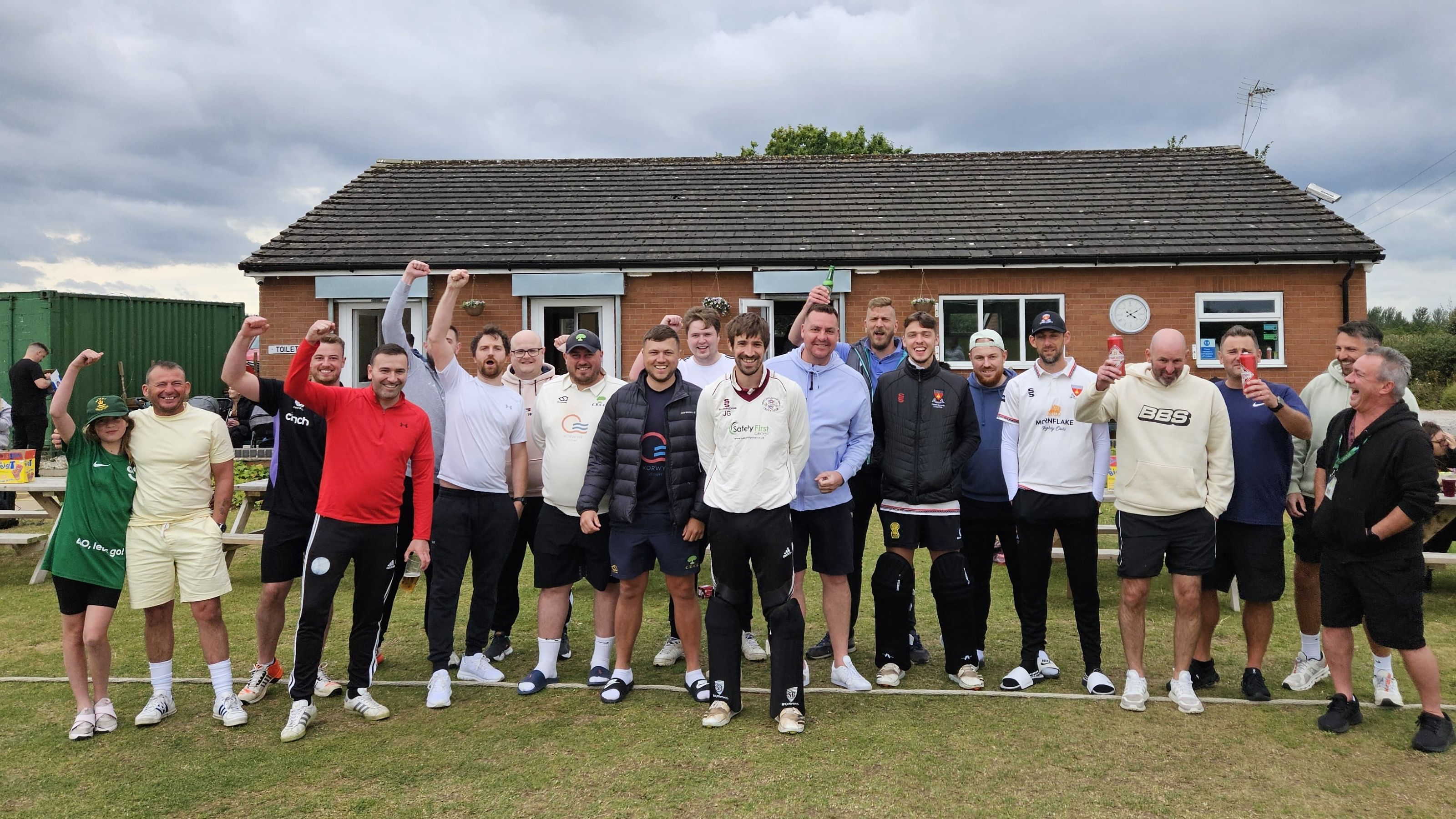 Cricket players cheering and smiling for a team photo.