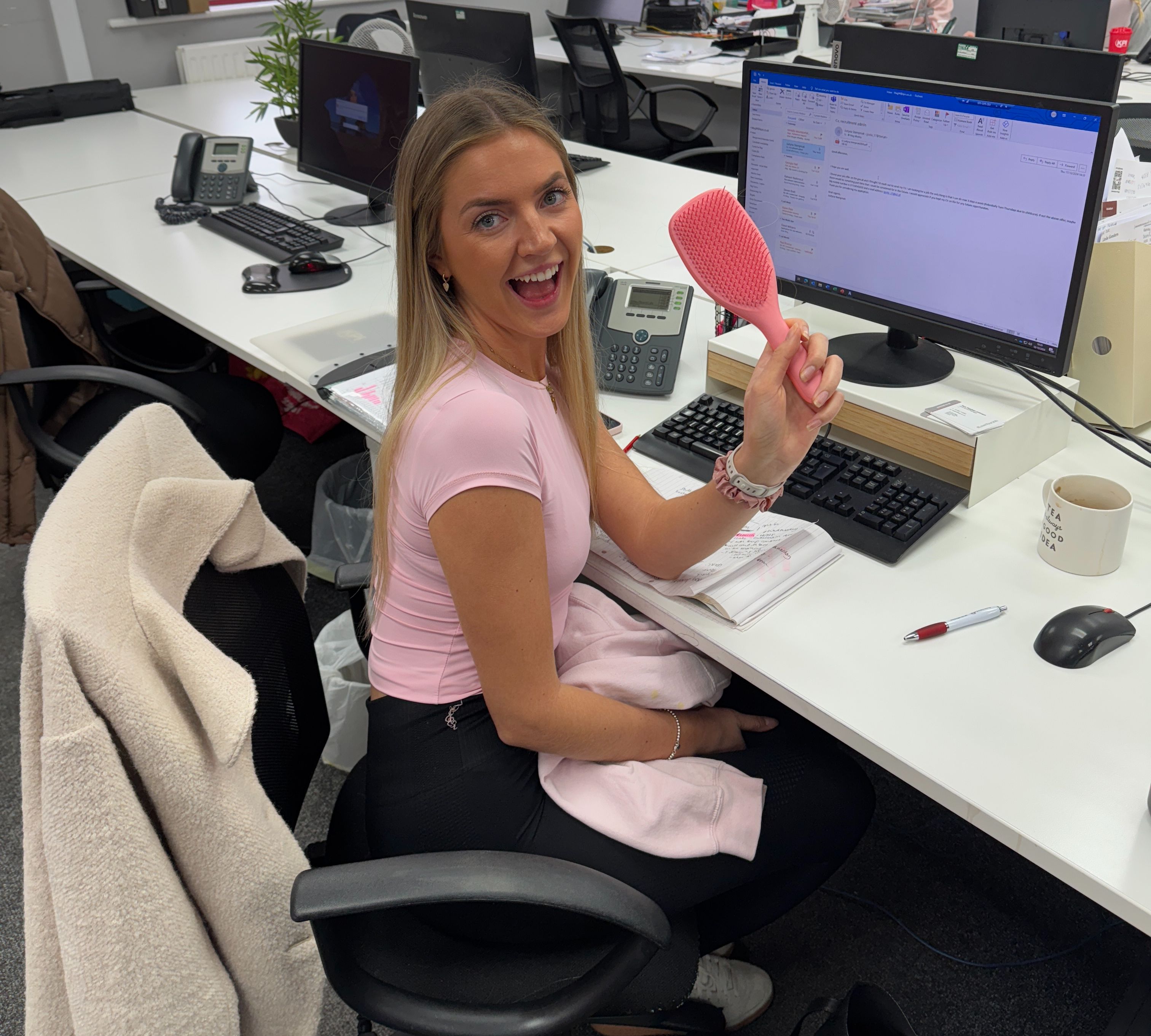 Girl in an office holding up a pink hairbrush