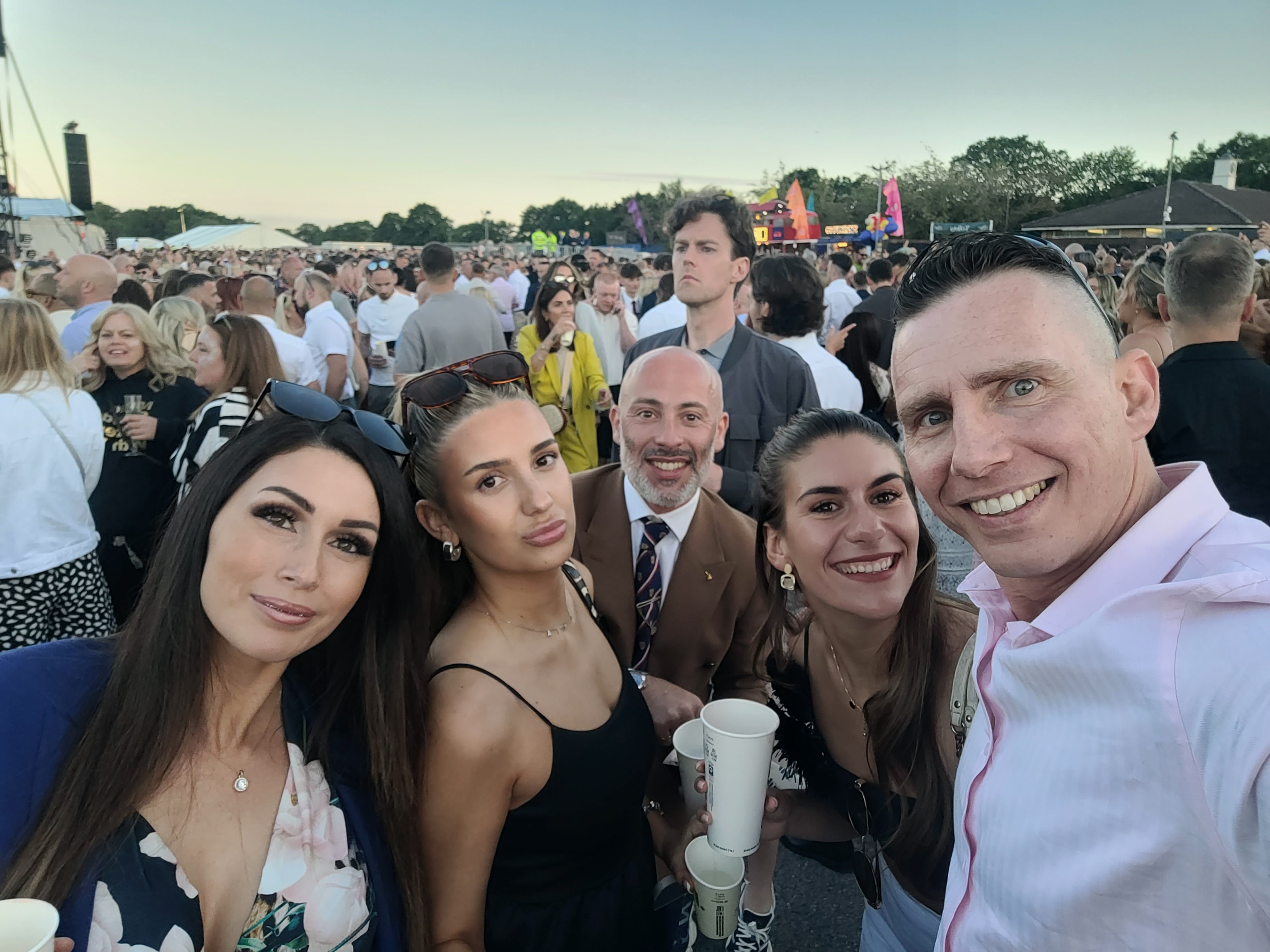 5 friends smiling at a racecourse.