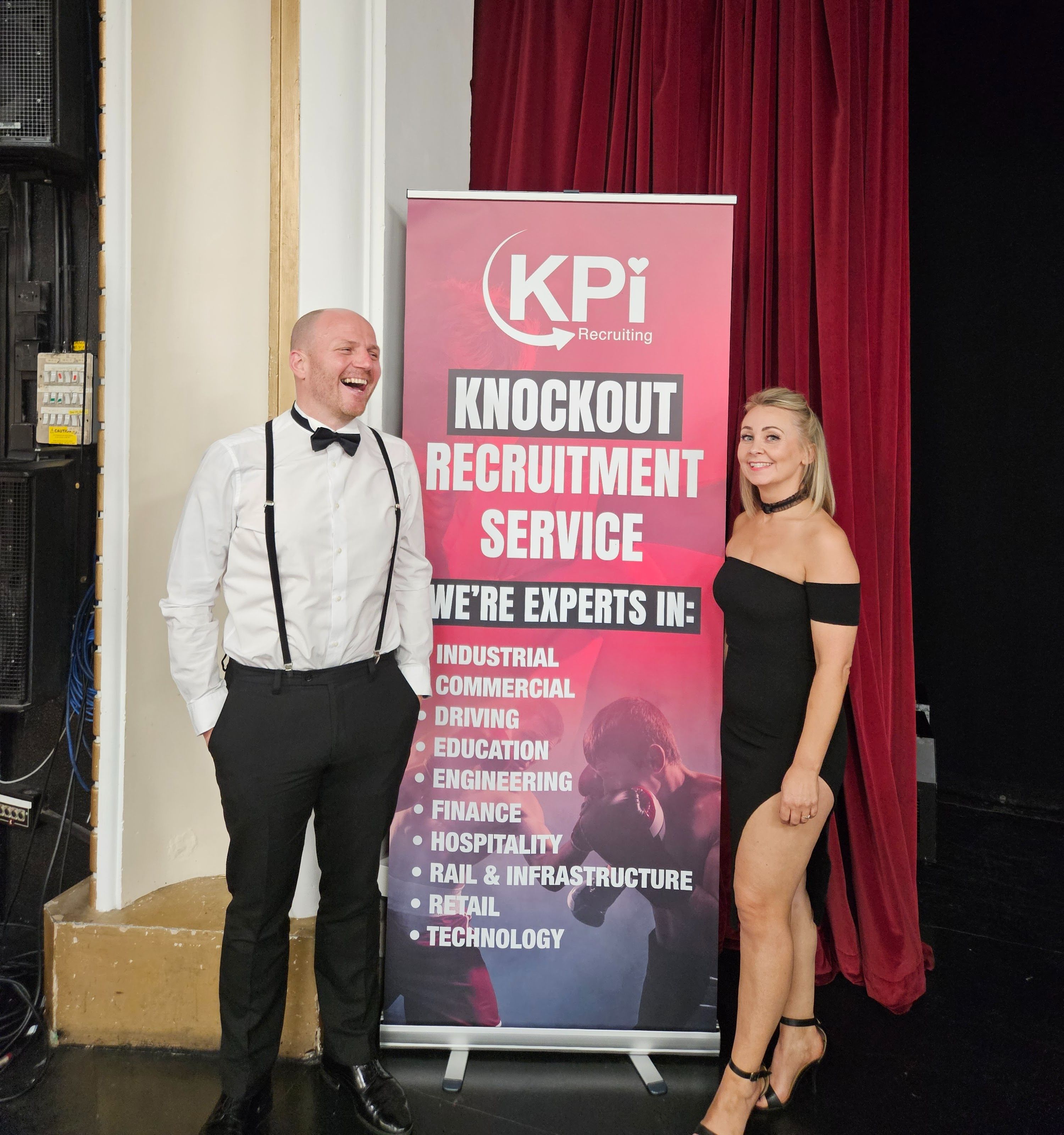 Man and woman dressed up pose in front of a roller banner.